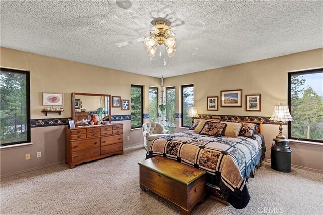 carpeted bedroom featuring ceiling fan and a textured ceiling