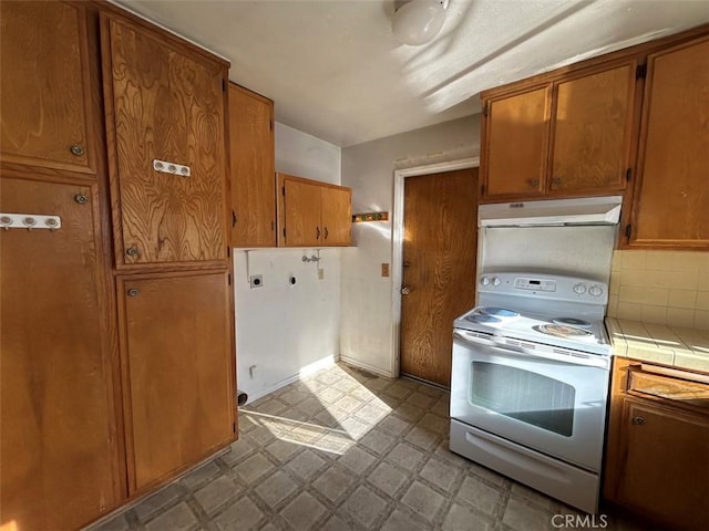 kitchen with tile countertops, decorative backsplash, and electric stove