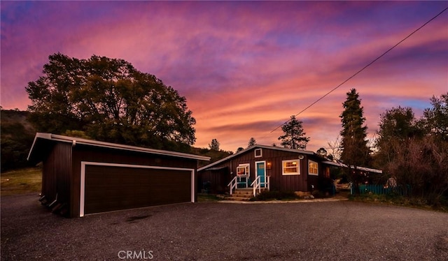 view of front of house featuring a garage, board and batten siding, an outdoor structure, and driveway