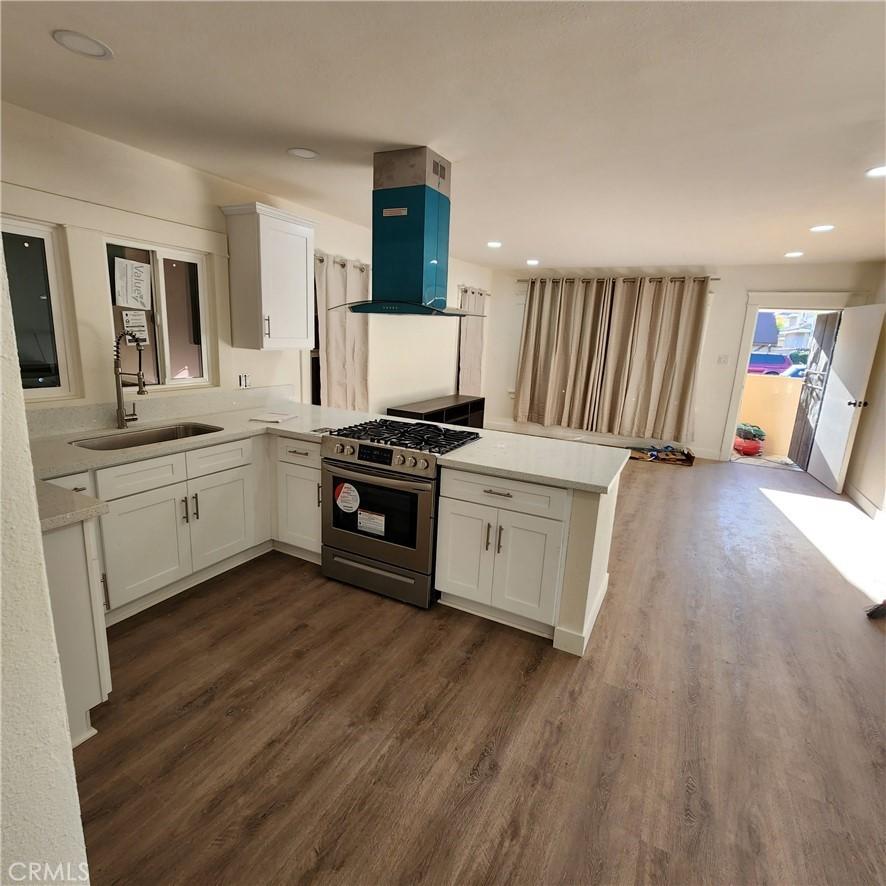 kitchen with white cabinets, kitchen peninsula, sink, and stainless steel gas range oven