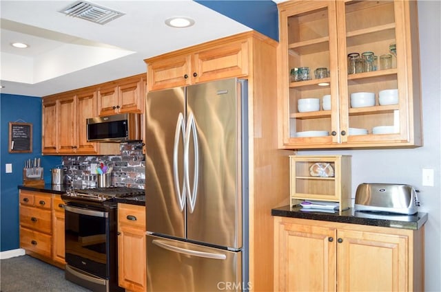kitchen featuring appliances with stainless steel finishes, decorative backsplash, glass insert cabinets, and visible vents