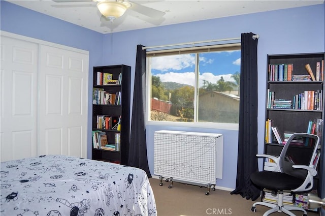 carpeted bedroom featuring ceiling fan, radiator, and a closet