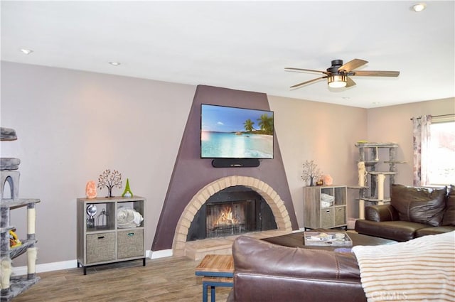 living room with ceiling fan, a fireplace, recessed lighting, baseboards, and wood finished floors
