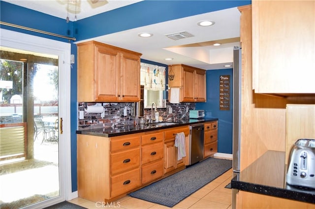 kitchen featuring visible vents, dark countertops, dishwasher, a sink, and backsplash