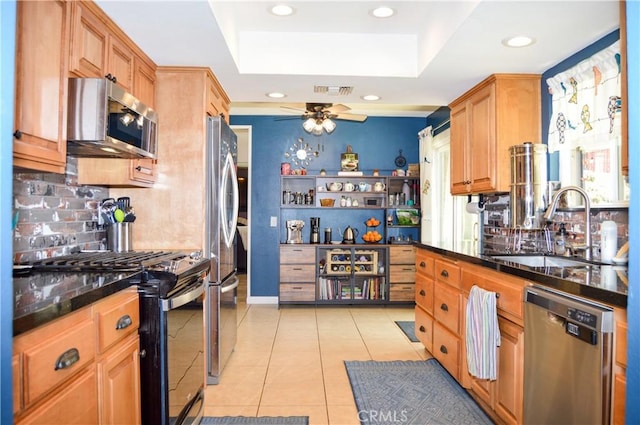 kitchen with a sink, appliances with stainless steel finishes, a tray ceiling, and recessed lighting