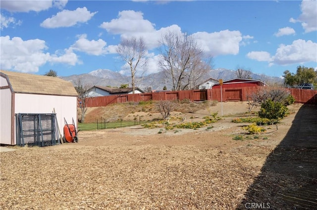 view of yard with fence, a storage unit, an outbuilding, and a mountain view