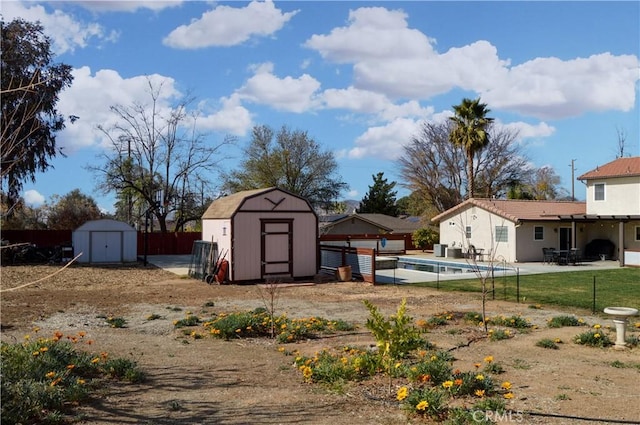 view of yard with a storage shed, an outbuilding, a patio area, fence, and a fenced in pool