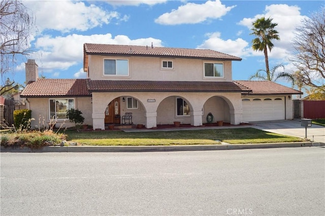 mediterranean / spanish house with a garage, stucco siding, a chimney, concrete driveway, and a tiled roof