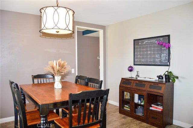 dining space with baseboards and wood finished floors