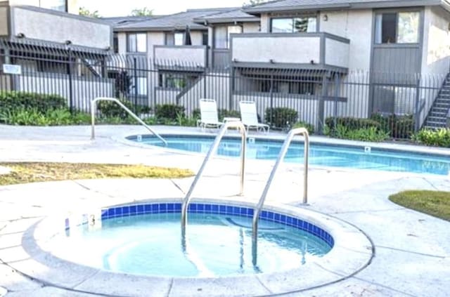 view of swimming pool with a hot tub