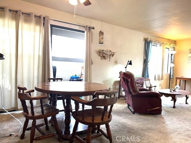 carpeted dining area with ceiling fan