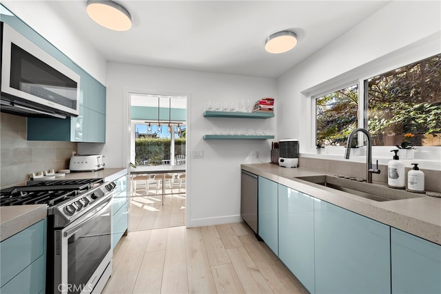 kitchen featuring appliances with stainless steel finishes, blue cabinets, sink, and decorative backsplash