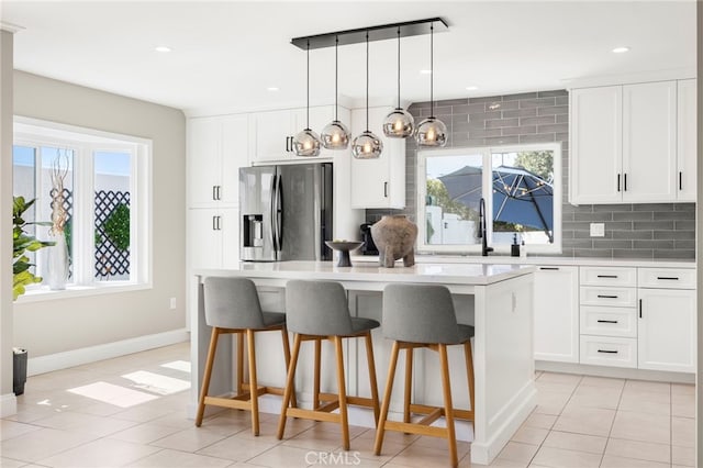 kitchen featuring a wealth of natural light, a kitchen island, backsplash, and stainless steel fridge with ice dispenser