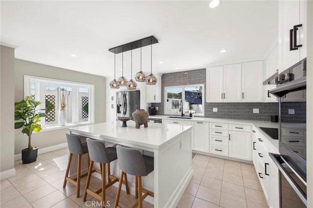 kitchen with light tile patterned floors, a breakfast bar area, stainless steel fridge with ice dispenser, a center island, and tasteful backsplash