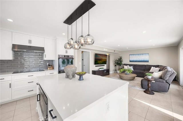 kitchen featuring light tile patterned floors, a center island, light countertops, under cabinet range hood, and backsplash