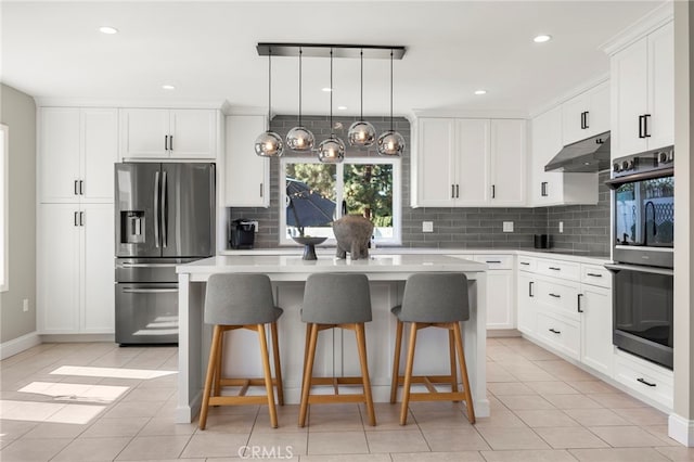 kitchen with appliances with stainless steel finishes, light countertops, under cabinet range hood, and decorative backsplash