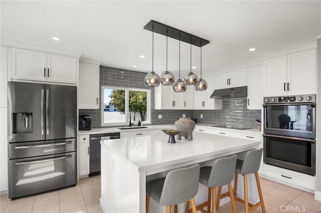 kitchen featuring white cabinets, stainless steel appliances, light countertops, under cabinet range hood, and a sink