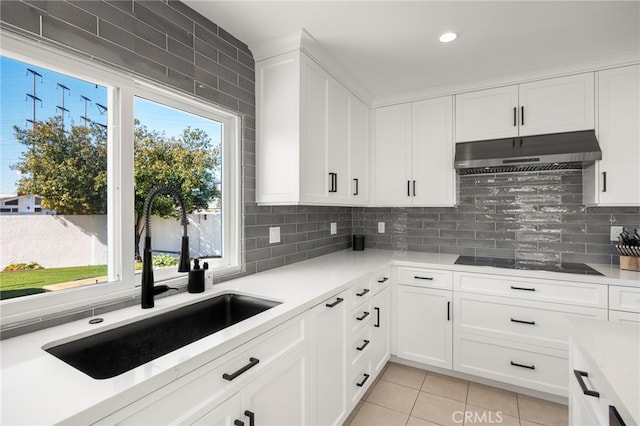 kitchen featuring black electric stovetop, tasteful backsplash, white cabinets, light tile patterned flooring, and under cabinet range hood