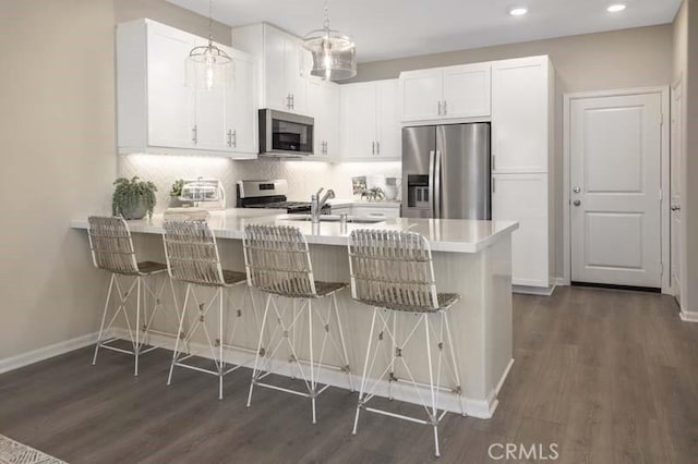 kitchen featuring pendant lighting, white cabinetry, a breakfast bar, and appliances with stainless steel finishes