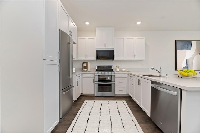 kitchen featuring dark wood finished floors, stainless steel appliances, light countertops, white cabinetry, and a sink