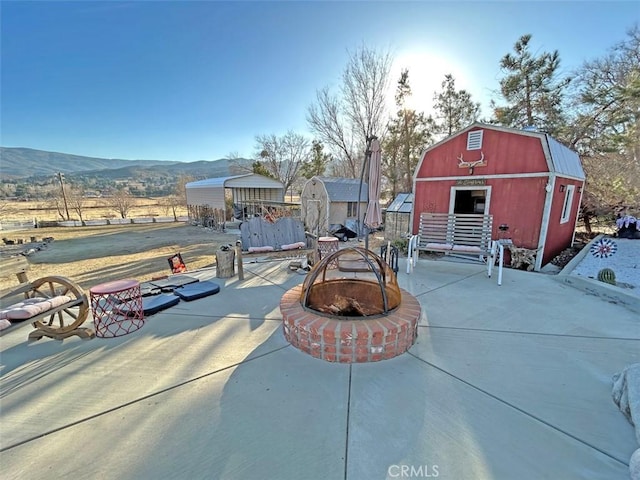 view of patio with a storage shed, an outdoor fire pit, and a mountain view