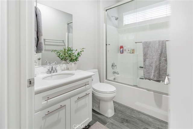 full bathroom featuring vanity, hardwood / wood-style floors, shower / bath combination with glass door, and toilet