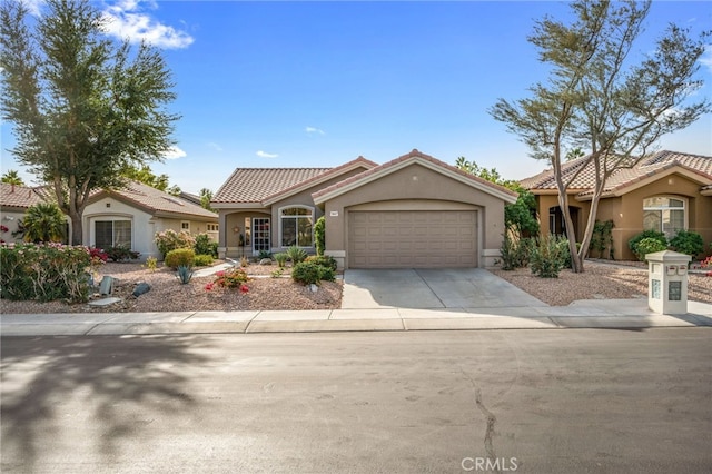 mediterranean / spanish-style house with a garage, concrete driveway, a tiled roof, and stucco siding