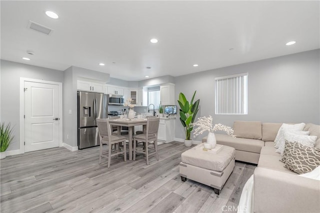 living room with sink and light hardwood / wood-style flooring