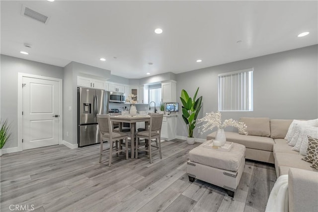 living room featuring sink and light hardwood / wood-style floors