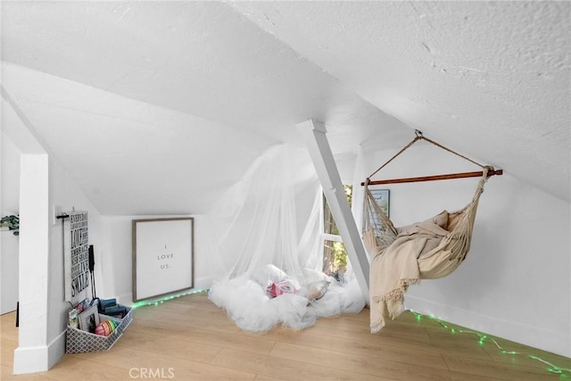 additional living space with lofted ceiling, hardwood / wood-style floors, and a textured ceiling