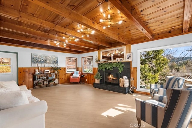 living room with beamed ceiling, a fireplace, light wood-type flooring, and wooden ceiling