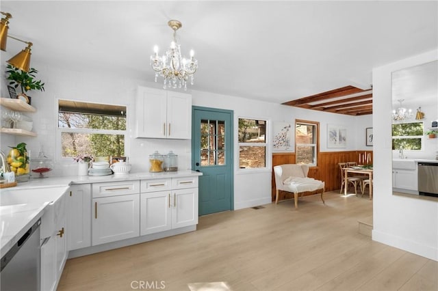 kitchen featuring white cabinetry, stainless steel dishwasher, decorative light fixtures, and a chandelier