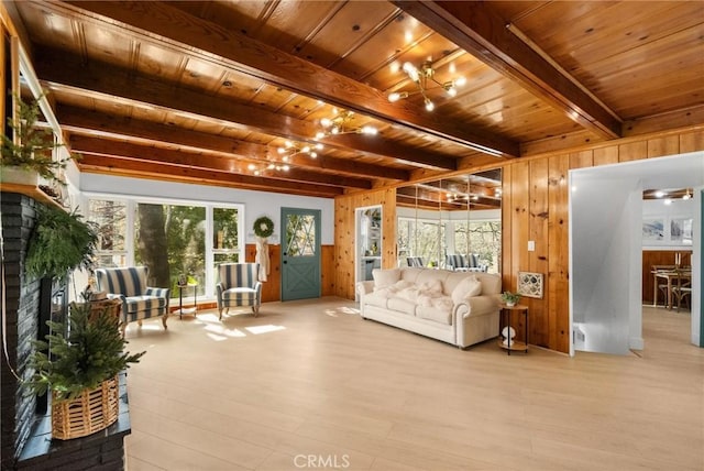 living room with wood walls, beamed ceiling, wood ceiling, a brick fireplace, and light hardwood / wood-style flooring