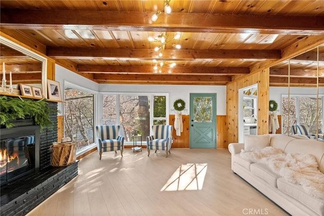 sunroom / solarium with beamed ceiling, a fireplace, and wood ceiling