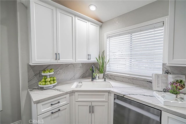 kitchen with sink, stainless steel dishwasher, white cabinets, and backsplash