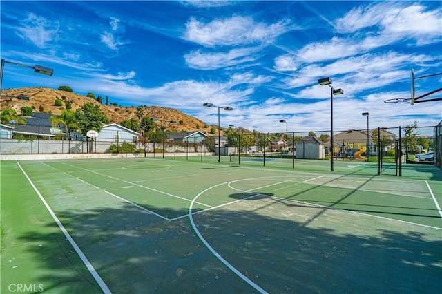 view of basketball court featuring a playground and a mountain view