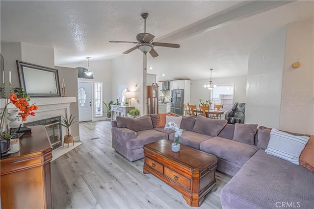 living room featuring lofted ceiling, ceiling fan with notable chandelier, a textured ceiling, and light wood-type flooring