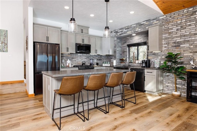 kitchen with a kitchen bar, recessed lighting, black appliances, backsplash, and a kitchen island
