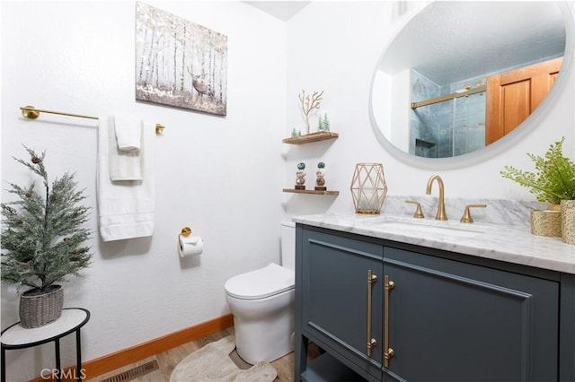 full bath featuring vanity, baseboards, a stall shower, toilet, and wood finished floors