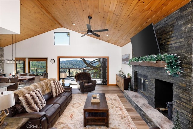 living area with high vaulted ceiling, a fireplace, a ceiling fan, wooden ceiling, and wood finished floors