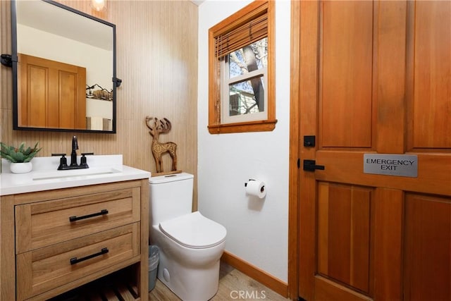 half bathroom with toilet, vanity, and baseboards