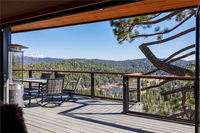wooden deck featuring a wooded view and a mountain view