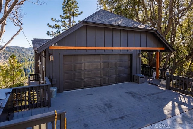 garage featuring driveway, a mountain view, and a view of trees