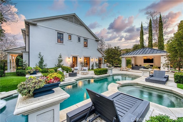 rear view of house with a fenced in pool, fence, an in ground hot tub, an outdoor living space with a fireplace, and a patio area