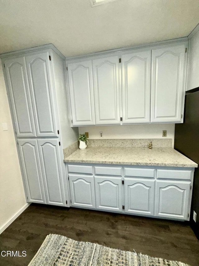 kitchen featuring white cabinetry, dark wood-type flooring, and stainless steel refrigerator