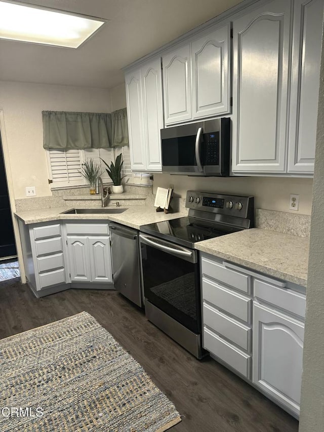 kitchen featuring sink, dark wood-type flooring, stainless steel appliances, and white cabinets