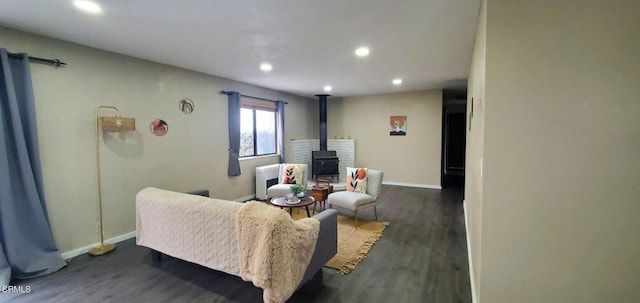 living room with dark wood finished floors, recessed lighting, baseboards, and a wood stove