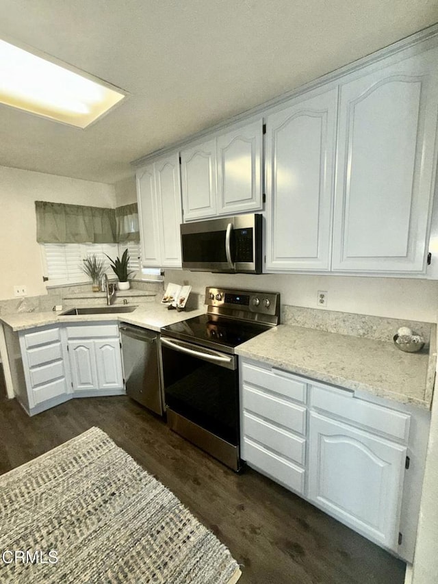 kitchen featuring dark wood-style flooring, white cabinetry, a sink, and stainless steel appliances