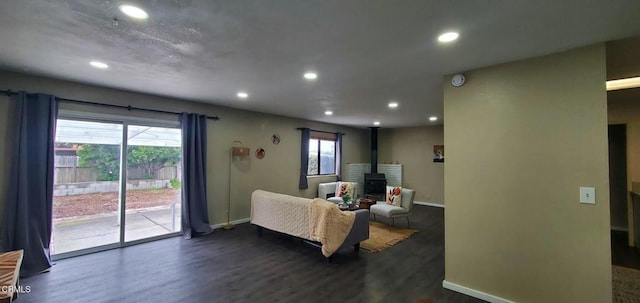 living room with dark wood-type flooring, a wealth of natural light, a wood stove, and recessed lighting