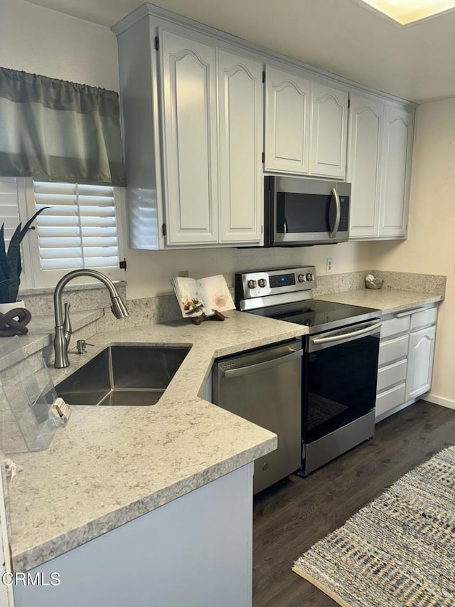 kitchen with dark wood-style floors, white cabinets, a sink, and stainless steel appliances